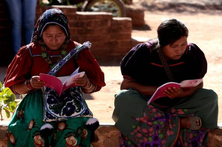 Deux femmes de la communauté autochtone Wixarika lisent un manuel officiel de l'Institut national électoral (INE) pendant un simulacre d'élection à deux semaines des scrutins du 2 juin, à Tuxpan de Bolaños, Etat du Jalisco, dans le nord-ouest du Mexique le 18 mai 2024 ( AE / ULISES RUIZ )
