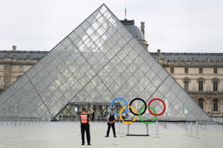 Un gendarme devant la Pyramide du Louvre, quelques heures avant le début de la cérémonie d'ouverture des Jeux olympiques de Paris 2024, le 26 juillet 2024 ( AFP / David GRAY )