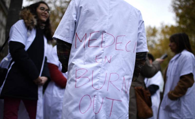Un psychiatre arbore le slogan "Médecin en burn-out" durant une manifestation des psychiatres hospitaliers devant le ministère de la Santé, à Paris, le 29 novembre 2022.  ( AFP / JULIEN DE ROSA )