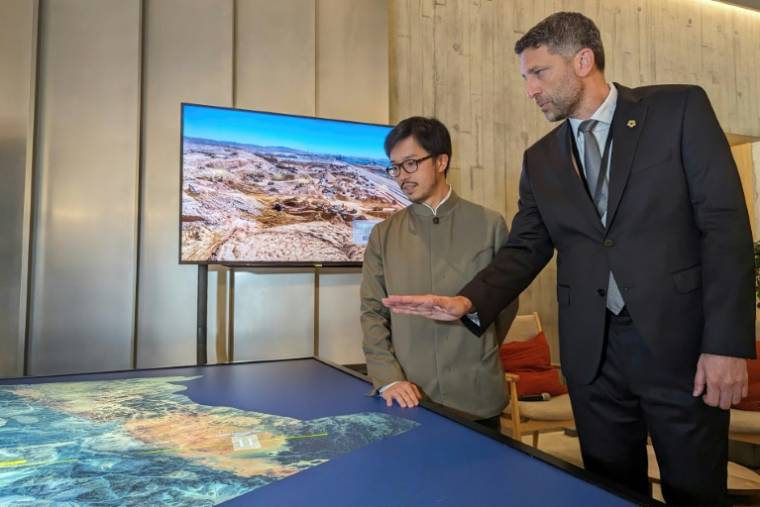 Tarek Qaddumi (d), directeur exécutif du mégaprojet NEOM en Arabie Saoudite, montre une carte des sites lors une exposition au musée M+ pour la culture visuelle, le 19 avril 2024 à Hong Kong  ( AFP / Holmes CHAN )