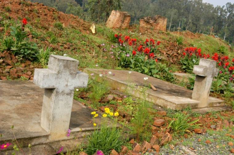 Photo du 16 janvier 2004 montrant des tombes devant les ruines de l'église Notre-Dame de la Visitation à Nyange, où environ 2.000 Tutsi ont été assassinés pendant le génocide au Rwanda en 1994 ( AFP / STR )