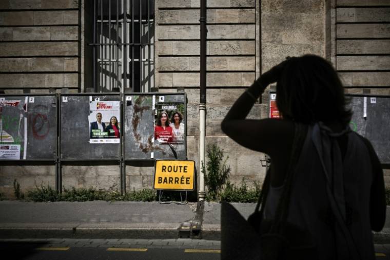 Une femme passe devant des panneaux électoraux avant les législatives à Bordeaux le 25 juin 2024 ( AFP / Philippe LOPEZ )
