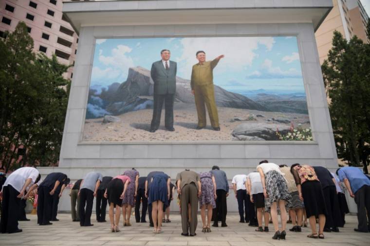 Des Nord-Coréens s'inclinent devant une fresque des dirigeants Kim Il Sung et Kim Jong Il, le 8 juillet 2021 à Pyongyang ( AFP / KIM Won Jin )