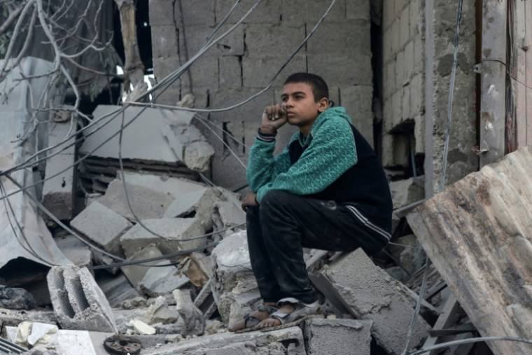 Un enfant palestinien assis dans les décombres d'un immeuble détruit par une frappe israélienne à Rafah, dans le sud de la bande de Gaza, le 2 avril 2024   ( AFP / MOHAMMED ABED )