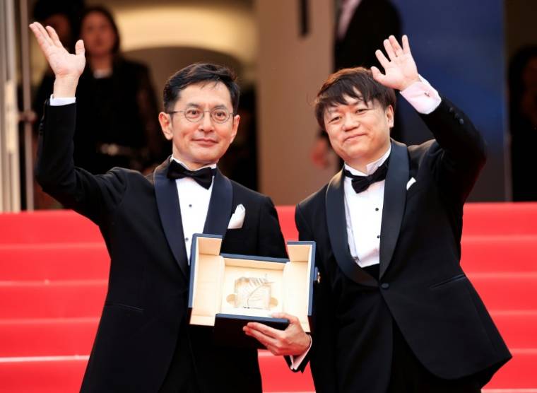 Le vice-président Kenichi Yoda (d) et le réalisateur japonais Gorö Miyazaki montrent la Palme d'or d'honneur décernée au studio d'animation japonais Ghibli, lors du 77e Festival de Cannes, le 20 mai 2024 ( AFP / Valery HACHE )
