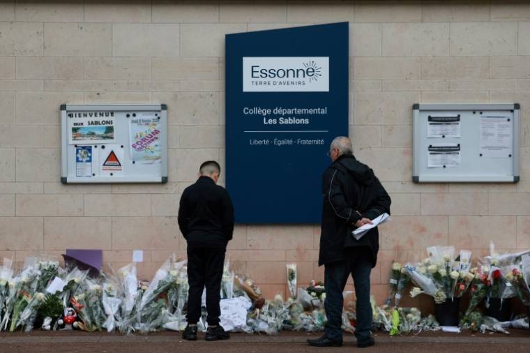 Des habitants regardent les fleurs déposées devant le collège des Sablons à Viry-Châtillon, en Essonne, le 7 avril 2024 ( AFP / Emmanuel Dunand )