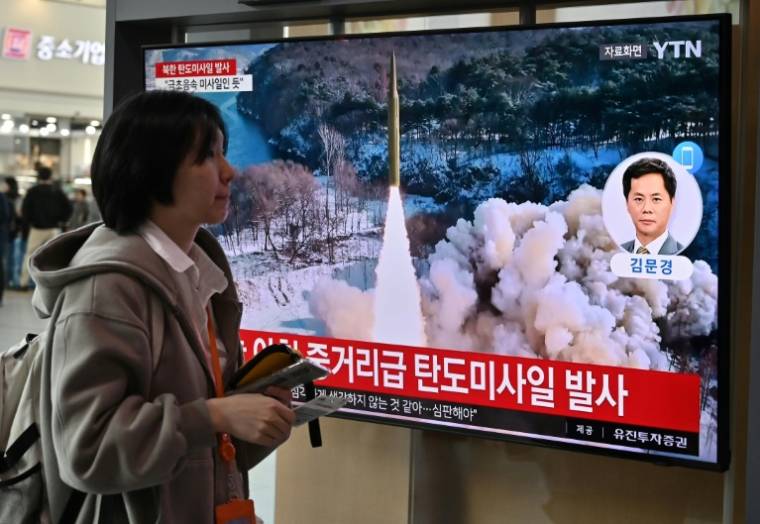Une femme passe devant des images télévisées d'un lancement de missile nord-coréen, le 2 avril 2024 à Séoul ( AFP / Jung Yeon-je )