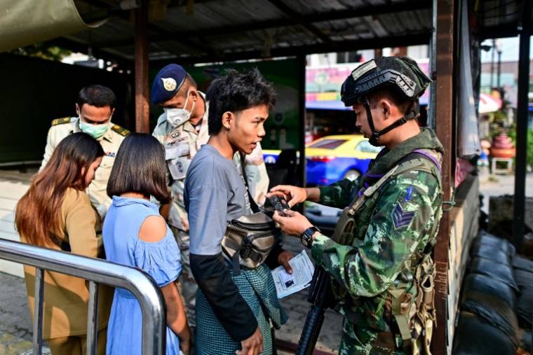 Des Birmans attendent après avoir traversé la frontière thaïlandaise au poste frontière de Tak, le 11 avril 2024 à Mae Sot ( AFP / MANAN VATSYAYANA )