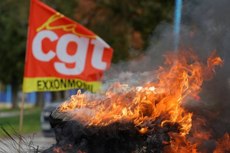 Un drapeau du syndicat CGT et des pneus enflammés devant la raffinerie de pétrole ExxonMobil