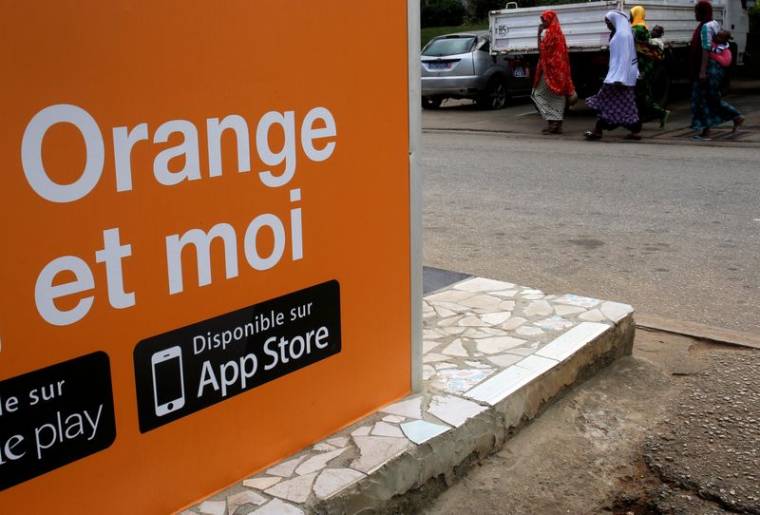 Des personnes marchent près d'un kiosque Orange money, alors qu'Orange lance ses premiers services Orange Bank à Abidjan