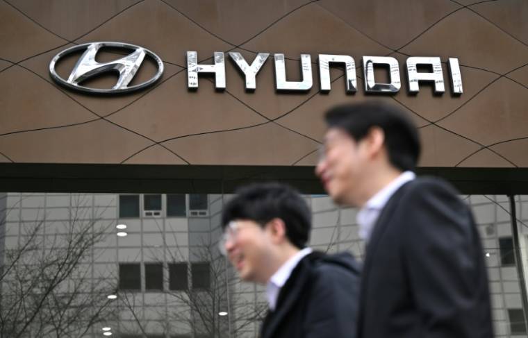 Des passants devant le logo d'une concession Hyundai à Séoul, en Corée du Sud, le 27 mars 2024 ( AFP / Jung Yeon-je )