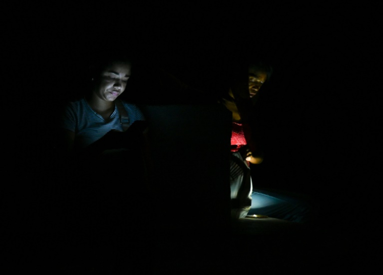 Des femmes s'illuminent avec leur téléphone portable à La Havane, le 20 octobre 2024, lors d'une panne de courant (AFP / YAMIL LAGE)