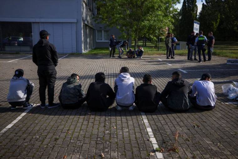 Des migrants sont assis par terre après avoir été arrêtés par la police allemande
