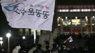 Un homme brandit un drapeau sud-coréen devant l'Assemblée nationale à Séoul, en Corée du Sud, le 4 décembre 2024 ( AFP / Anthony WALLACE )