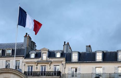 Photo d'un drapeau français qui flotte au-dessus de l'entrée du palais de l'Elysée