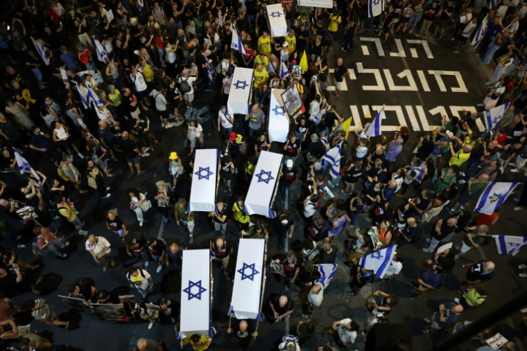 Des Israéliens portent des cercueils symboliques lors d'une manifestation antigouvernementale appelant à obtenir la libération des otages retenus à Gaza, devant le ministère israélien de la Défense à Tel-Aviv, le 5 septembre 2024 ( AFP / Jack GUEZ )