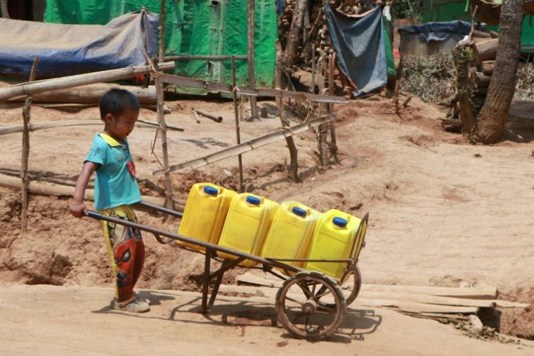 Un enfant transporte des bidons pour une distribution d'eau potable dans un camp de personnes déplacées à Demoso, dans l'État de Kayah, le 29 avril 2024 dans l'est de la Birmanie  ( AFP / STR )
