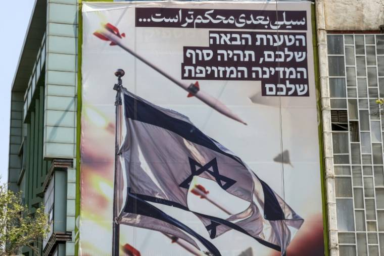 Affiche géante sur laquelle on peut voir des drones et des missiles autour d'un drapeau israélien déchiré, le 14 avril 2024 à Téhéran  ( AFP / ATTA KENARE )