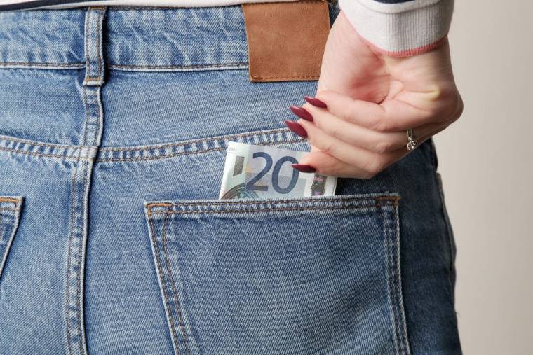(Crédits photo : Adobe Stock - Femme plaçant un billet de vingt dans la poche de son pantalon)