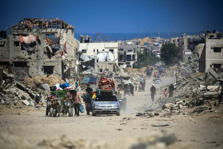 Des Palestiniens à pied et en voiture quittent Khan Younès, le sud de la bande de Gaza, au milieu des destructions, le 3 juillet 2024 ( AFP / Eyad BABA )