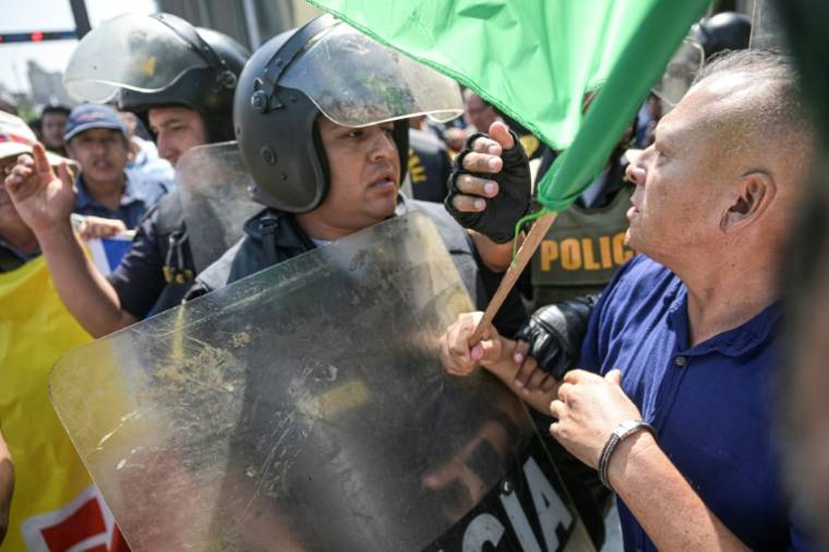 Des policiers séparent des partisans et des détracteurs de la présidente péruvienne Dina Boluarte, le 5 avril 2024 à Lima ( AFP / Ernesto BENAVIDES )