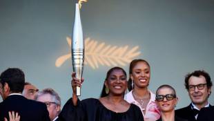 L'ancienne athlète Marie-José Pérec (c) tient la flamme olympique, avant la projection du film "Marcello Mio", lors du 77e Festival de Cannes, le 21 mai 2024 ( AFP / Valery HACHE )