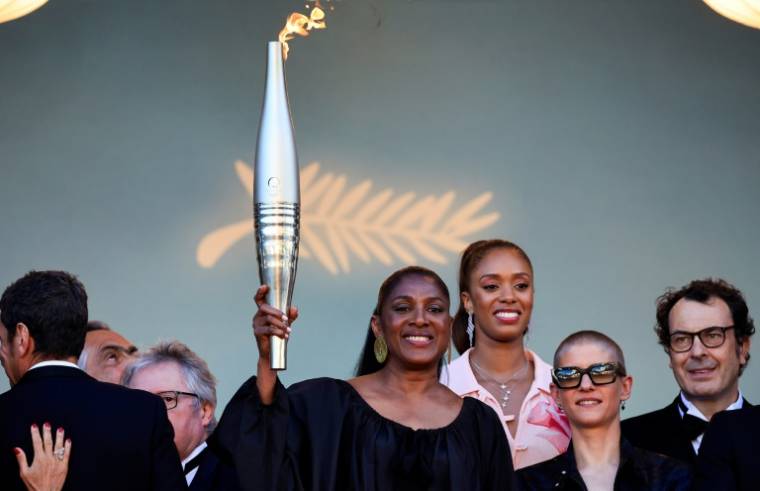 L'ancienne athlète Marie-José Pérec (c) tient la flamme olympique, avant la projection du film "Marcello Mio", lors du 77e Festival de Cannes, le 21 mai 2024 ( AFP / Valery HACHE )