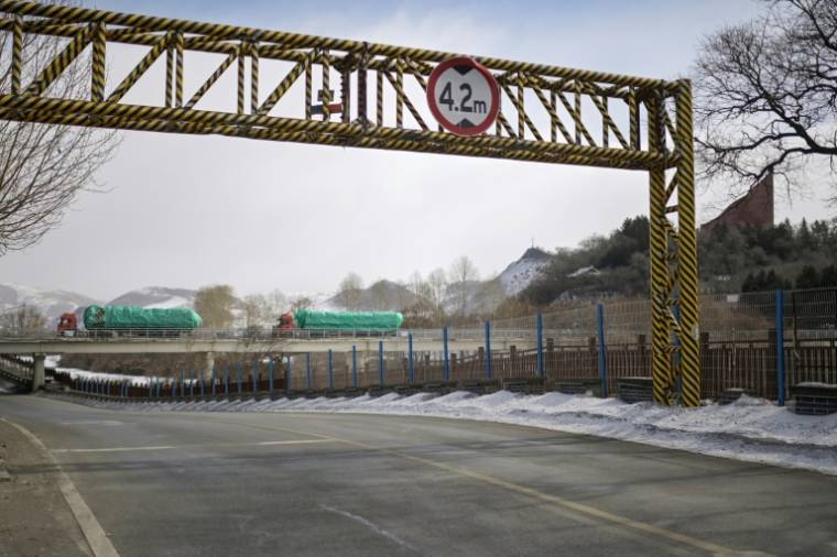 Des camions traversent le pont frontalier reliant les villes chinoise de Changbai (g) et  nord-coréenne de Hyesan, dans la province de Jilin, dans le nord-est de la Chine, le 1er mars 2024 ( AFP / Pedro PARDO )