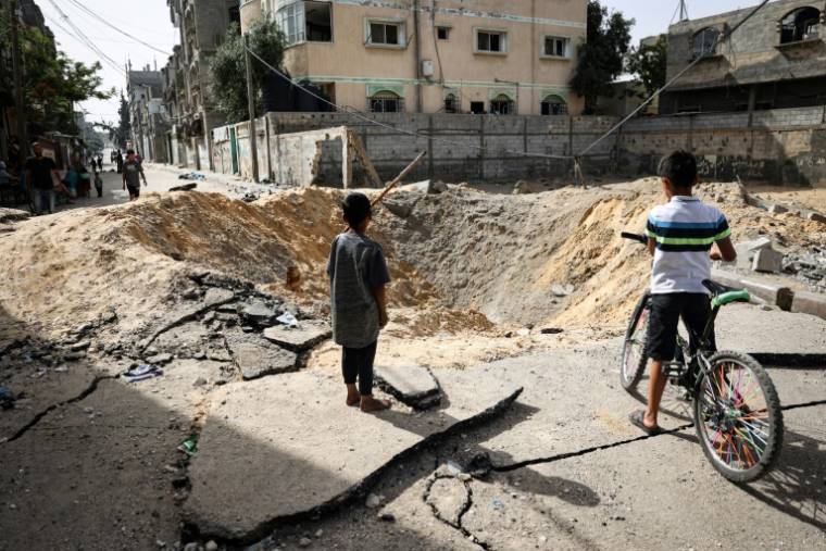 Des enfants devant un cratère causé par un bombardement israélien à Rafah, dans le sud de la bande de Gaza, le 18 mai 2024 ( AFP / - )