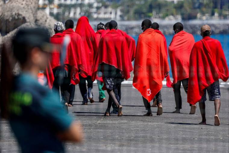 Des migrants se dirigent vers une tente de la Croix-Rouge après avoir débarqué d'un navire des garde-côtes espagnols, dans le port d'Arguineguin.