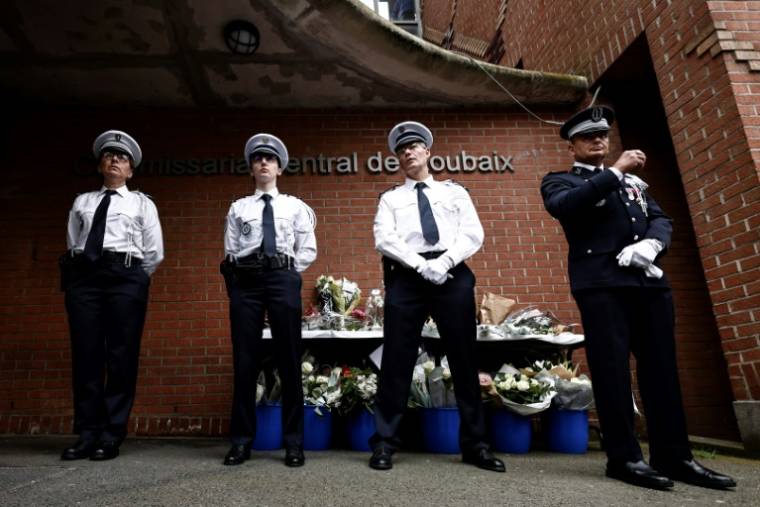 Des policiers se tiennent près d'un mémorial improvisé en hommage aux trois policiers tués le 21 mai devant un commissariat de Roubaix, dans le nord de la France, le 23 mai 2023 ( AFP / Sameer Al-Doumy )