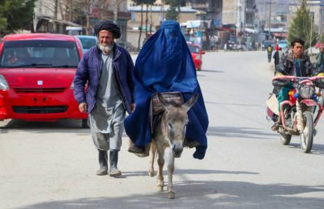 Une femme en burqa, se déplace à dos d'âne, accompagnée d'un homme à Fayzabad, le 14 mars 2024 en Afghanistan  ( AFP / OMER ABRAR )