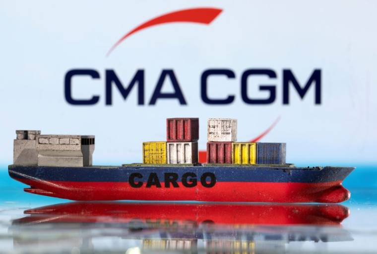Un modèle de bateau cargo est photographié devant le logo de CMA CGM.
